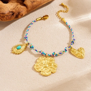 Detailed view of handmade braided gold bracelet with turquoise eye and flower charms