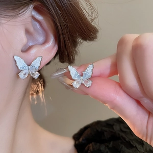 Détail de boucles d'oreilles papillon en argent avec ailes blanches et strass