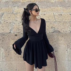 Detail of a black V-neck mini dress with bell sleeves and pleated waist on a model