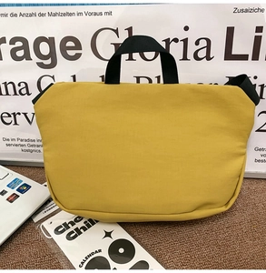 Macro shot of yellow canvas crossbody bag featuring durable black nylon woven handles