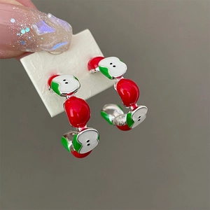 Macro view of silver apple hoop earrings with red and green glossy enamel fruit charms