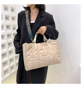 Detail of beige quilted tote bag featuring an ethnic patterned wide shoulder strap