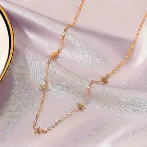 Collana dorata minimalista con cinque ciondoli a stella scintillanti su seta morbida