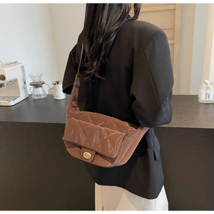 Detail of brown quilted saddle bag with gold swivel lock on adjustable shoulder strap