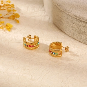Golden stainless steel hoop earrings with colorful cubic zirconia on light fabric background