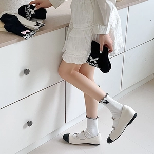 Detail of JK style white socks featuring black ruffle trim and decorative bows