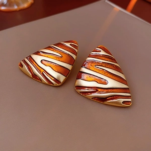 Macro shot of triangle vintage earrings with amber tiger-stripe pattern and gold base