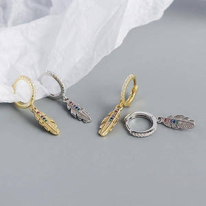 Detail of silver feather earrings with colorful zircon stones in gold and silver