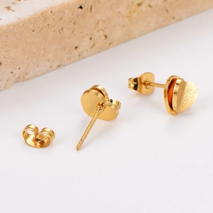 Close-up of golden heart earrings with matte finish and butterfly backings