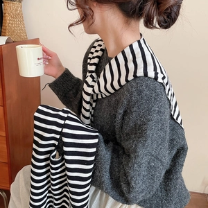 Detail of dark grey knit sweater paired with a striped shawl in a cozy lifestyle setting