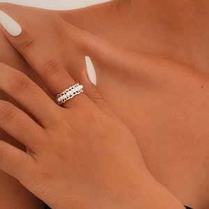 Detailed close-up of a hollowed silver ring band set with white pearls on a model finger