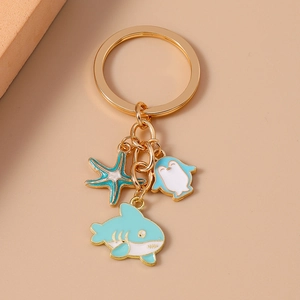 Detail of marine keychain with shark, penguin, and starfish enamel charms on gold chain