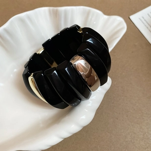 Detail of wide stretch bracelet with black acrylic resin and gold metal geometric modules