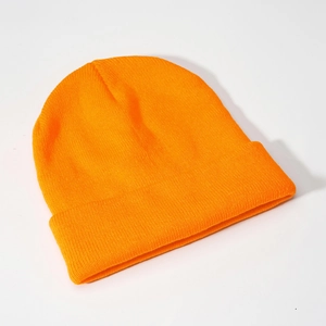 Detailed top view of a bright orange ribbed knit beanie with cuffed brim on white background