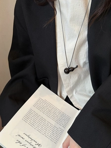 Detail of a black obsidian gourd pendant necklace styled with a minimalist outfit