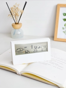 Digital desk clock showing time temperature and humidity on an open book in cozy light