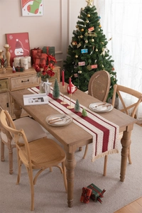Detailed close-up of beige cotton linen Christmas table runner with red tassel fringe details