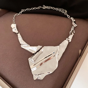 Detailed close-up of an irregular geometric silver necklace with a crinkled texture finish