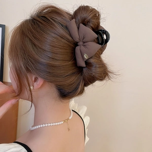 Detail of elegant coffee brown fabric bow hair claw clip worn in a classic updo
