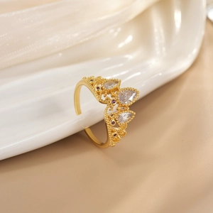 Detailed close-up of crown ring with golden finish and clear teardrop zircons