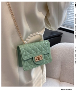 Close-up of mint green silicone jelly bag with faux pearl handle and gold chain strap