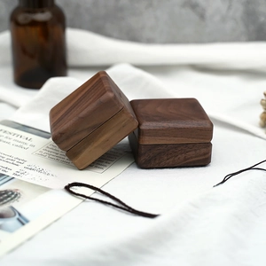 Détail de boîtes à alliances en bois de noyer sur un fond en tissu au style rustique