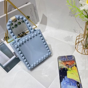 Close-up of light blue PVC mini bag with 3D square rivets and geometric rivet texture