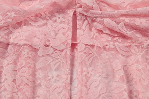 Close-up of pink lace dress fabric featuring intricate floral crochet and sheer texture
