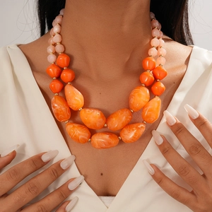 Close-up of double-layer beaded necklace with orange marble resin and pink accents