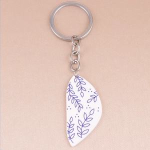 Detail of bohemian acrylic keychain with blue floral patterns on a white pendant