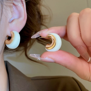Close-up of C-shaped earrings with 18k gold plating and white resin finish