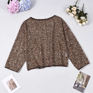 Detailed view of brown sequin mesh fabric on a long sleeve top with soft lighting