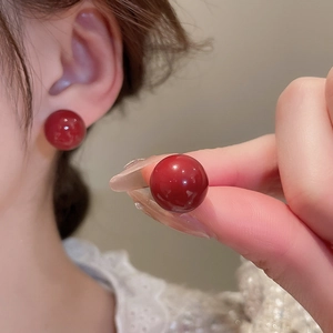 Detail shot of bright red round geometric stud earrings with polished finish on model