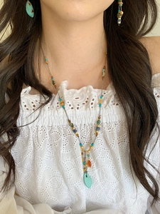 Detailed shot of ethnic necklace set with turquoise and red agate on a model