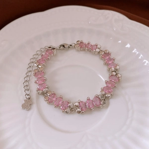 Detail of silver bracelet featuring pink marquise stones and small bear pendant charm
