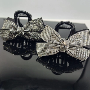 Elegant black bow hair claws with full rhinestone inlay on reflective surface