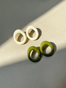 Detailed view of geometric resin hoop earrings in cream white and olive green
