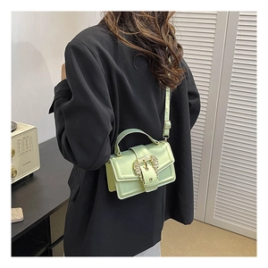 Detail of light green crossbody bag featuring a golden baroque metal buckle and sleek flap