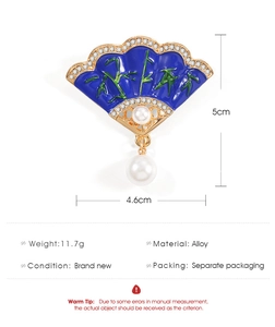 Detail view of fan-shaped brooch with blue enamel, bamboo pattern, and white pearl drop