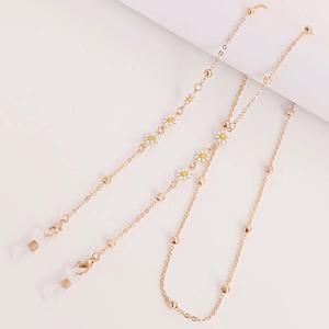 Detail of gold chain with white and yellow enamel daisy charms and silicone loops