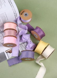 Détail de rubans en satin à volants aux tons pastels sur des rouleaux de carton