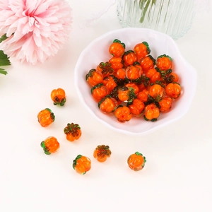 Handmade orange pumpkin glass beads for DIY jewelry making displayed in a white bowl