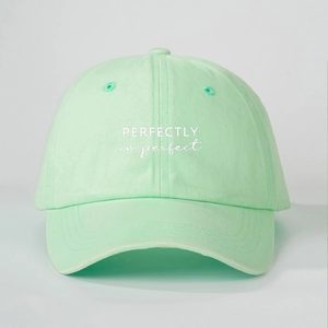 Macro detail of the embroidered slogan and washed cotton texture on mint green baseball cap