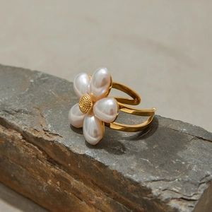 Detailed view of a gold flower ring with pearl petals on a grey stone pedestal