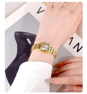 Detail of square gold watch with Roman numerals on a vintage dial with metal chain strap