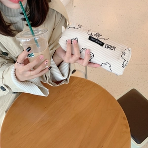 Close-up of corduroy pencil case with cartoon dog print held by model in natural light