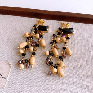 Detail of vintage earrings with square black gems and long beaded wooden tassels