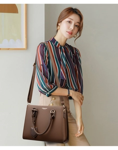 Close-up of brown leather tote bag featuring gold hardware and fashion brand lettering