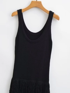 Détail de la robe tricotée noire sans manches avec des franges denses sur l'ourlet inférieur
