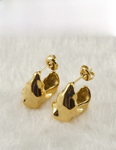Detailed macro view of gold-plated stainless steel earrings with molten lava texture